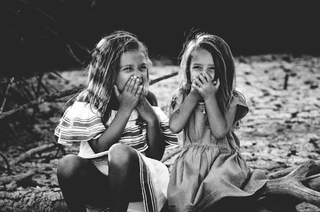 young girls laughing with hands on mouths