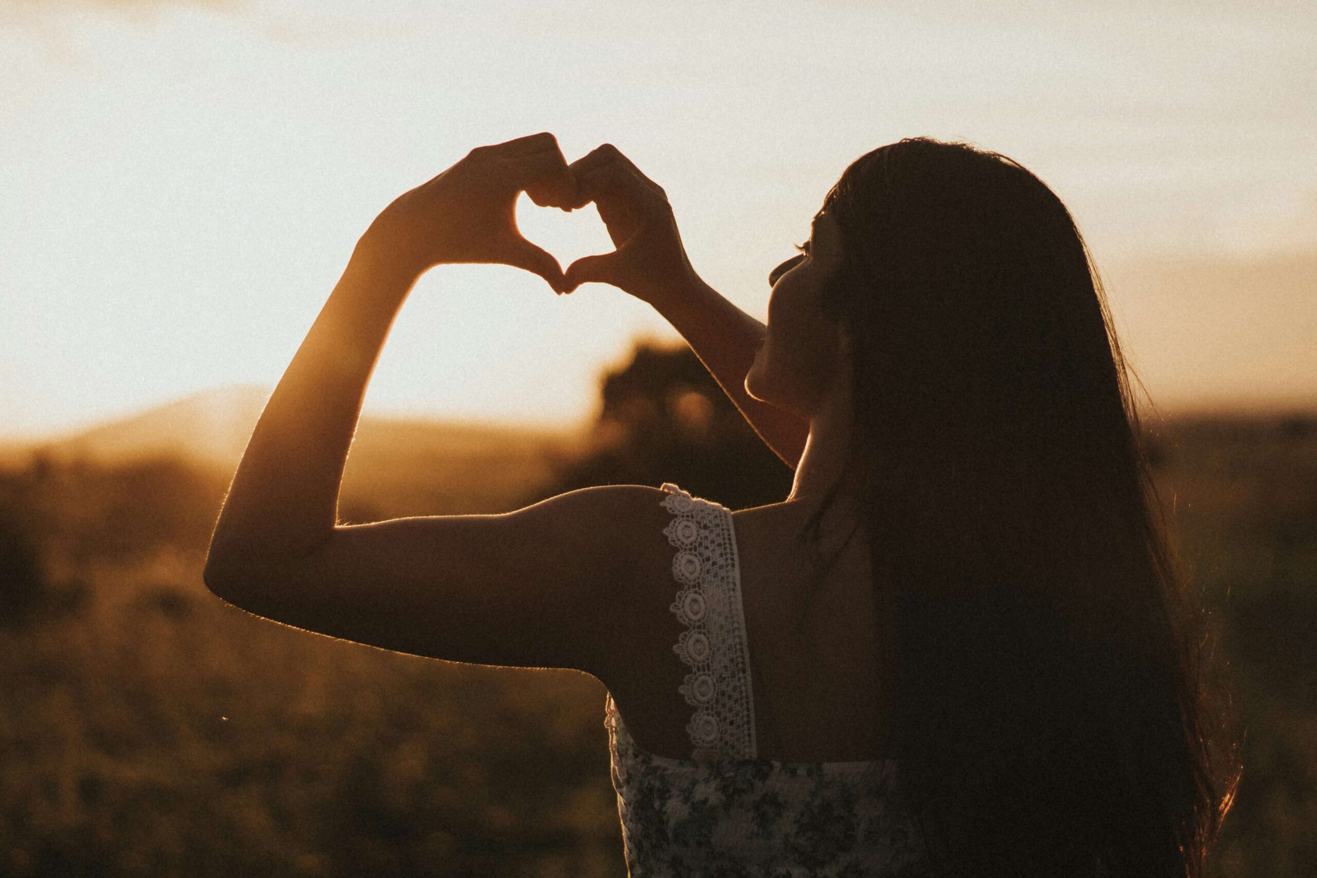 A woman holding her hands into a heart. If you're looking to navigate your HSP traits, get started with a therapist for women in NYC, NY. Contact me today to get started with women issues therapy.