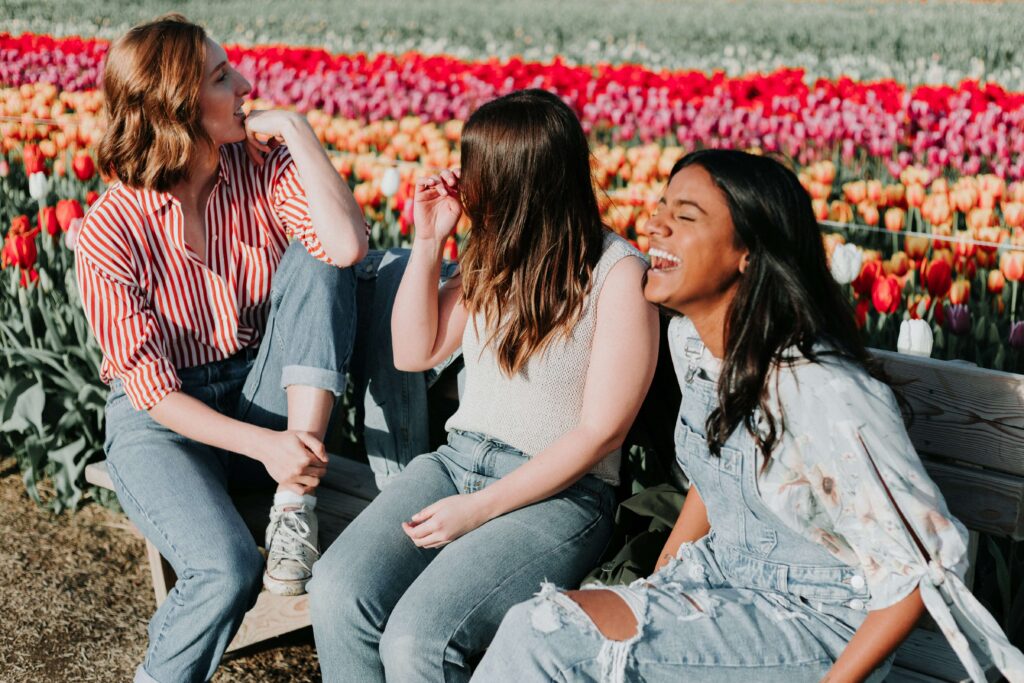 A group of young women laughing together by tulips. Work with a women's therapist in NYC, NY today! I offer women's issues therapy to help. 