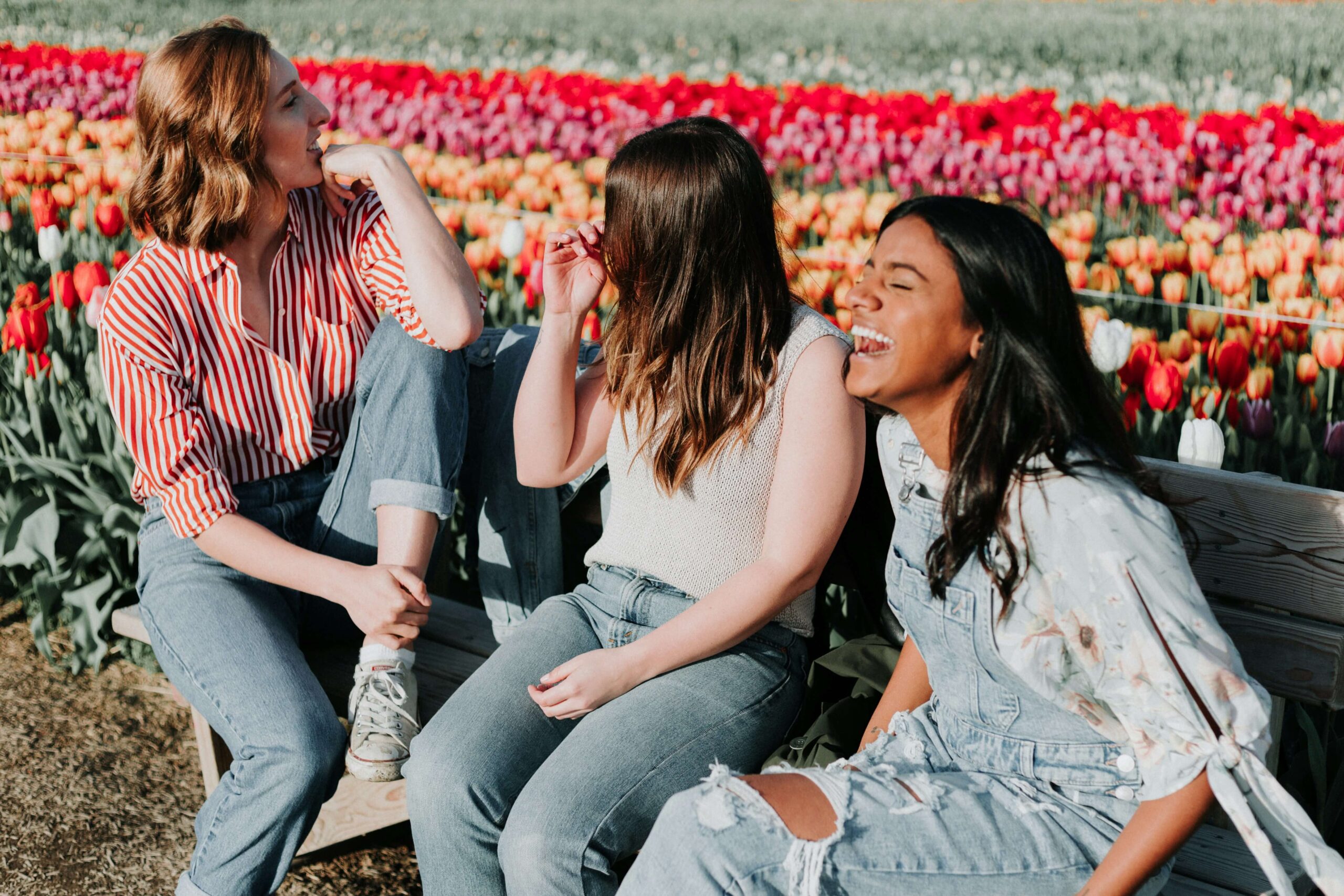 Three young women laughing by tulips. With the support from a women's therapist in NYC, NY, you can work on coping strategies for your anxiety. Begin women's therapy today!
