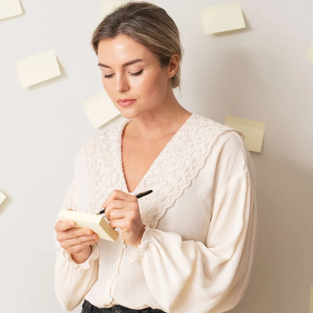 Woman writing notes on sticky notes while organizing tasks and reminders